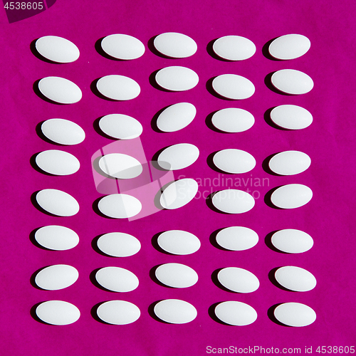 Image of White pills on pink background.