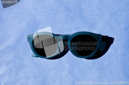 Image of Stylish sunglasses with shadow on blue background. 