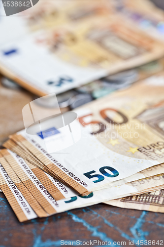 Image of Pile of fifty euro banknotes and coins. 