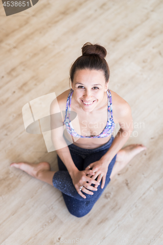 Image of Fit sporty active girl in fashion sportswear sitting on the floor in yoga studio. Active urban lifestyle