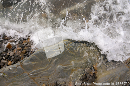 Image of The wave rolls on a rocky shore, aerial view