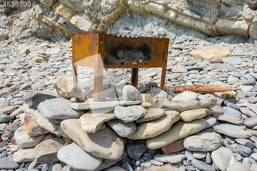 Image of On a rocky shore is a small abandoned barbecue