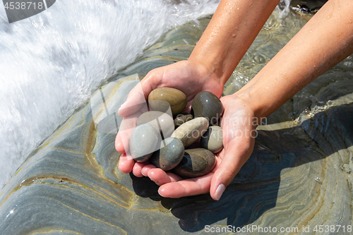 Image of Palms hold a pile of stones on the seashore