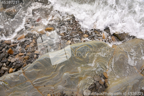 Image of A wave rolls onto a rocky sea beach