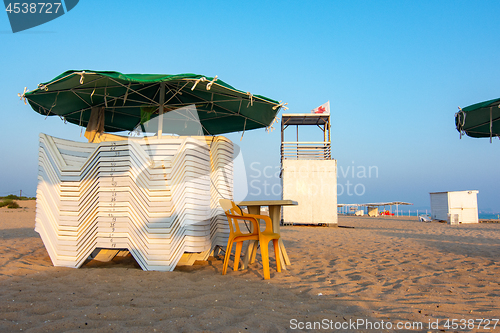 Image of Folded sun loungers and an empty lifeguard post on a deserted sandy beach