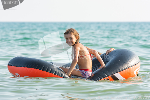 Image of Cheerful girl rides on an inflatable boat at sea