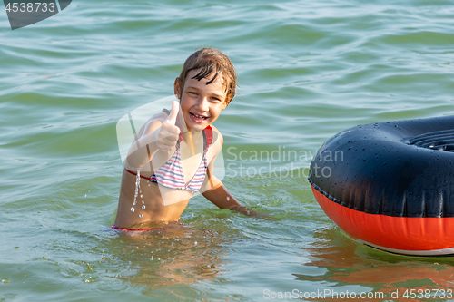 Image of Cheerful girl shows thumb up by jumping from a boat