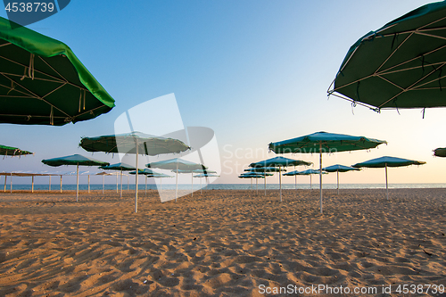 Image of Opened umbrellas on a deserted evening sandy beach