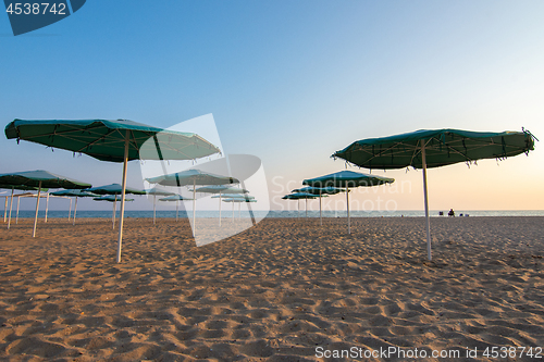 Image of Opened sandy beach umbrellas at sunset