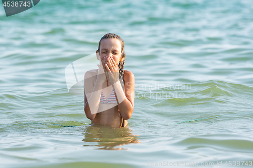 Image of The girl drowned in sea water and wipes her nose and face with her hands