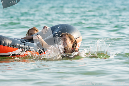 Image of Two girls dive from an inflatable boat into the sea