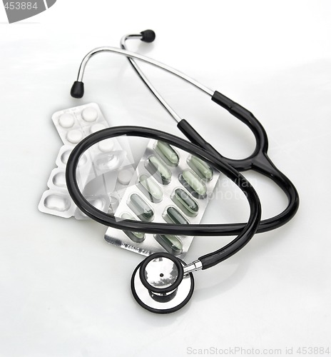 Image of stethoscope and pills on white