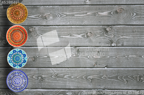 Image of Set of decorative ceramic plates hand-painted with acrylic paints on a wooden background with place for text.