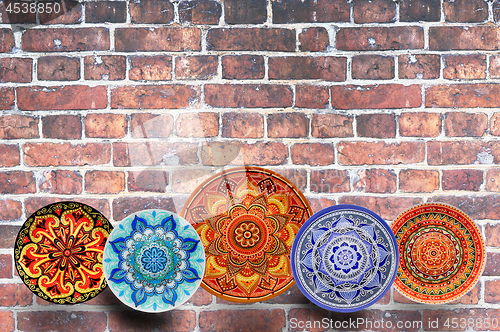Image of Set of decorative ceramic plates hand-painted with acrylic paints on a brick background with place for text.