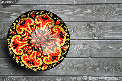 Image of Decorative ceramic plate, hand painted with acrylic paints on a wooden background. Closeup with place for text.