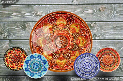 Image of Set of decorative ceramic plates hand-painted with acrylic paints on a wooden background with place for text.