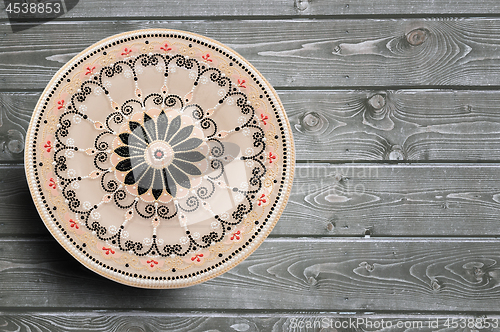 Image of Decorative ceramic plate, hand painted with acrylic paints on a wooden background. Closeup with place for text.