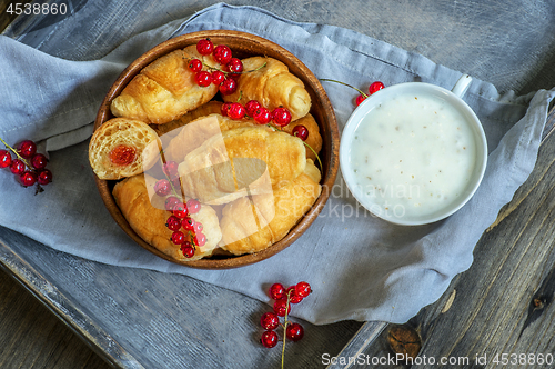 Image of Croissants with currant berries on a wooden tray. The concept of a wholesome breakfast.