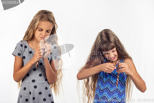 Image of Two girls try to open a plastic bag of caramel candies
