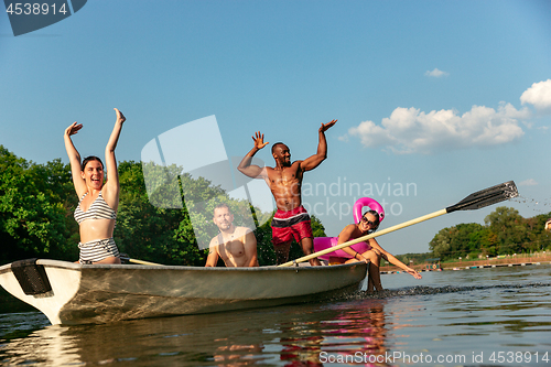 Image of Happy group of friends having fun, laughting and swimming in river