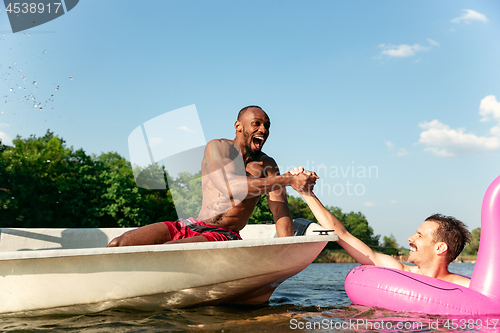 Image of Happy friends having fun, laughting and swimming in river