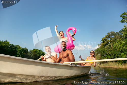 Image of Happy group of friends having fun, laughting and swimming in river