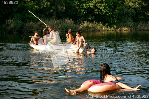 Image of Happy group of friends having fun, laughting and swimming in river