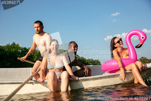 Image of Happy group of friends having fun, laughting and swimming in river