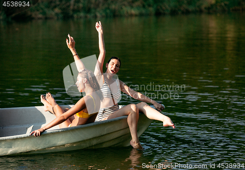 Image of Happy group of friends having fun, laughting and swimming in river