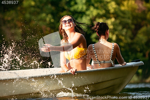 Image of Happy group of friends having fun, laughting and swimming in river