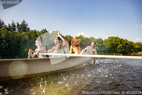 Image of Happy group of friends having fun, laughting and swimming in river