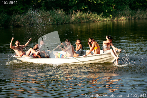 Image of Happy group of friends having fun, laughting and swimming in river