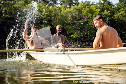 Image of Happy group of friends having fun, laughting and swimming in river