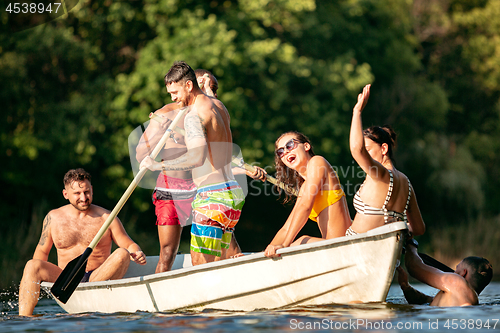 Image of Happy group of friends having fun, laughting and swimming in river