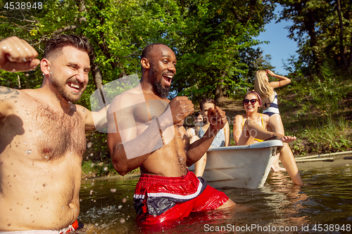 Image of Happy group of friends having fun, laughting and swimming in river