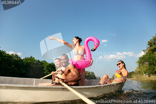 Image of Happy group of friends having fun, laughting and swimming in river