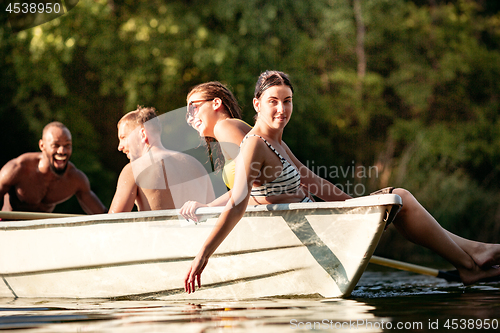 Image of Happy group of friends having fun, laughting and swimming in river