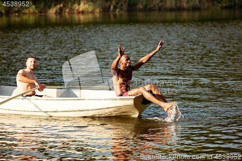 Image of Happy group of friends having fun, laughting and swimming in river