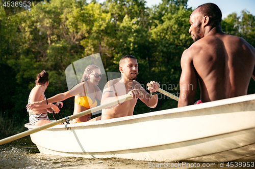 Image of Happy group of friends having fun, laughting and swimming in river