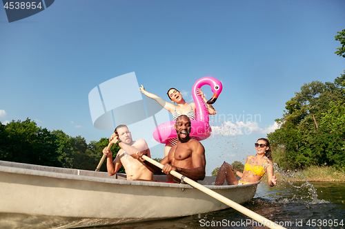 Image of Happy group of friends having fun, laughting and swimming in river