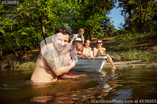 Image of Happy group of friends having fun, laughting and swimming in river