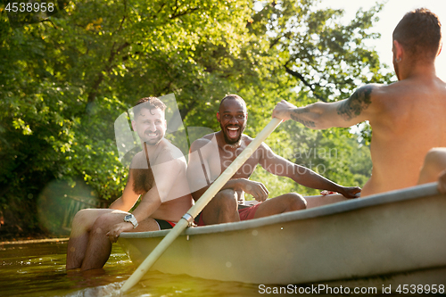 Image of Happy group of friends having fun, laughting and swimming in river