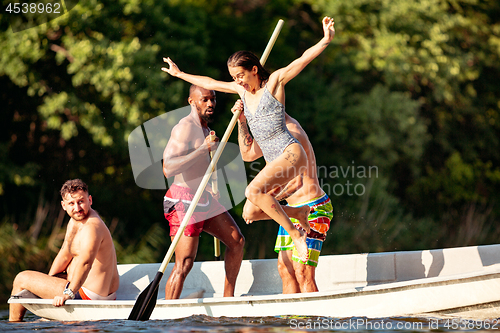 Image of Happy group of friends having fun, laughting and swimming in river