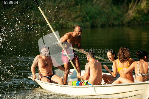 Image of Happy group of friends having fun, laughting and swimming in river