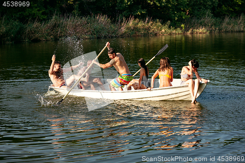 Image of Happy group of friends having fun, laughting and swimming in river