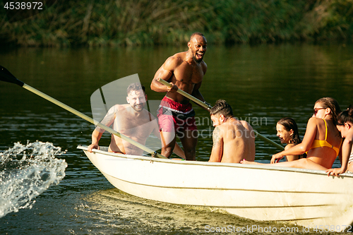 Image of Happy group of friends having fun, laughting and swimming in river