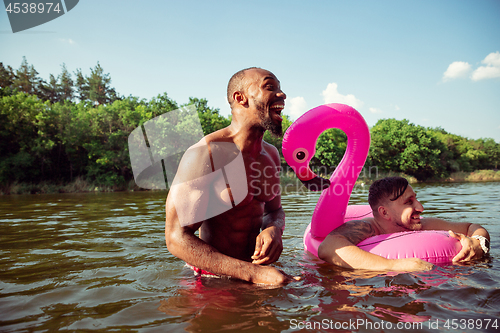 Image of Happy group of friends having fun, laughting and swimming in river