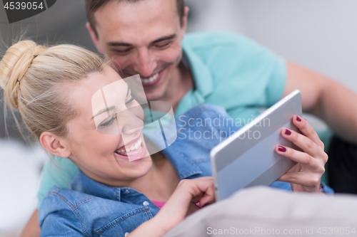 Image of couple relaxing at  home with tablet computers