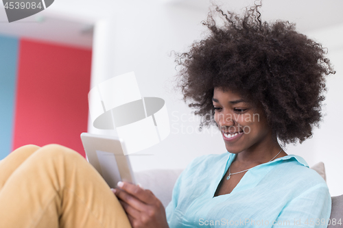 Image of african american woman at home using digital tablet
