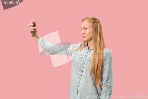 Image of Portrait of a happy smiling casual girl showing blank screen mobile phone isolated over pink background